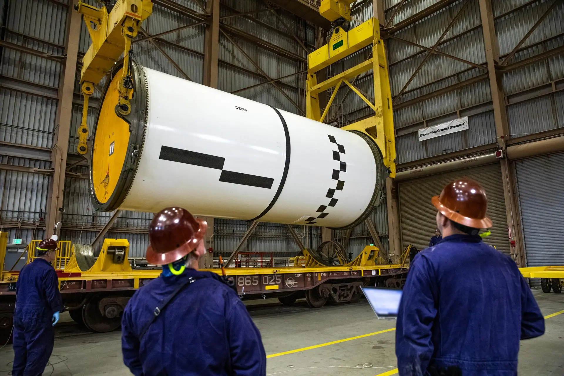 Engineers and technicians process the right forward center segment of the Space Launch System solid rocket boosters for the Artemis II mission inside the Rotation, Processing and Surge Facility at NASA’s Kennedy Space Center in Florida. ©NASA