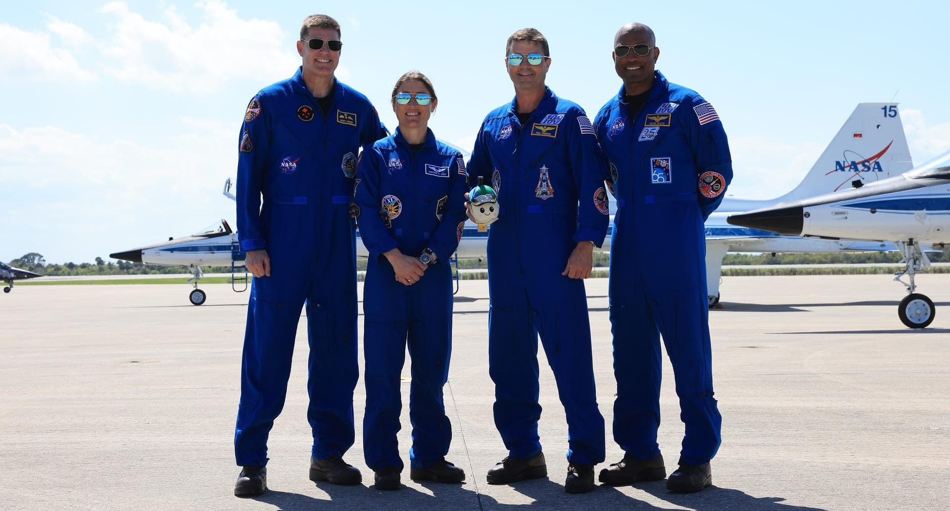 Artemis II's Jeremy Hansen (left), Christina Koch (center left), Reid Wiseman (center right), and Victor Glover (right) after arriving at the Kennedy Space Center on March 27th 2026, with 'Rise' being held in the middle. ©Kim Shiflett/NASA